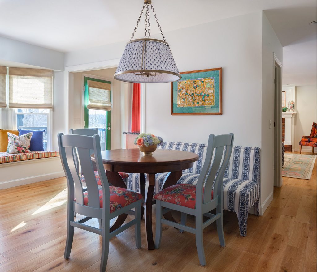 St. Charles breakfast room with a striped banquette, painted blue chairs, block-print pendant, and a window seat