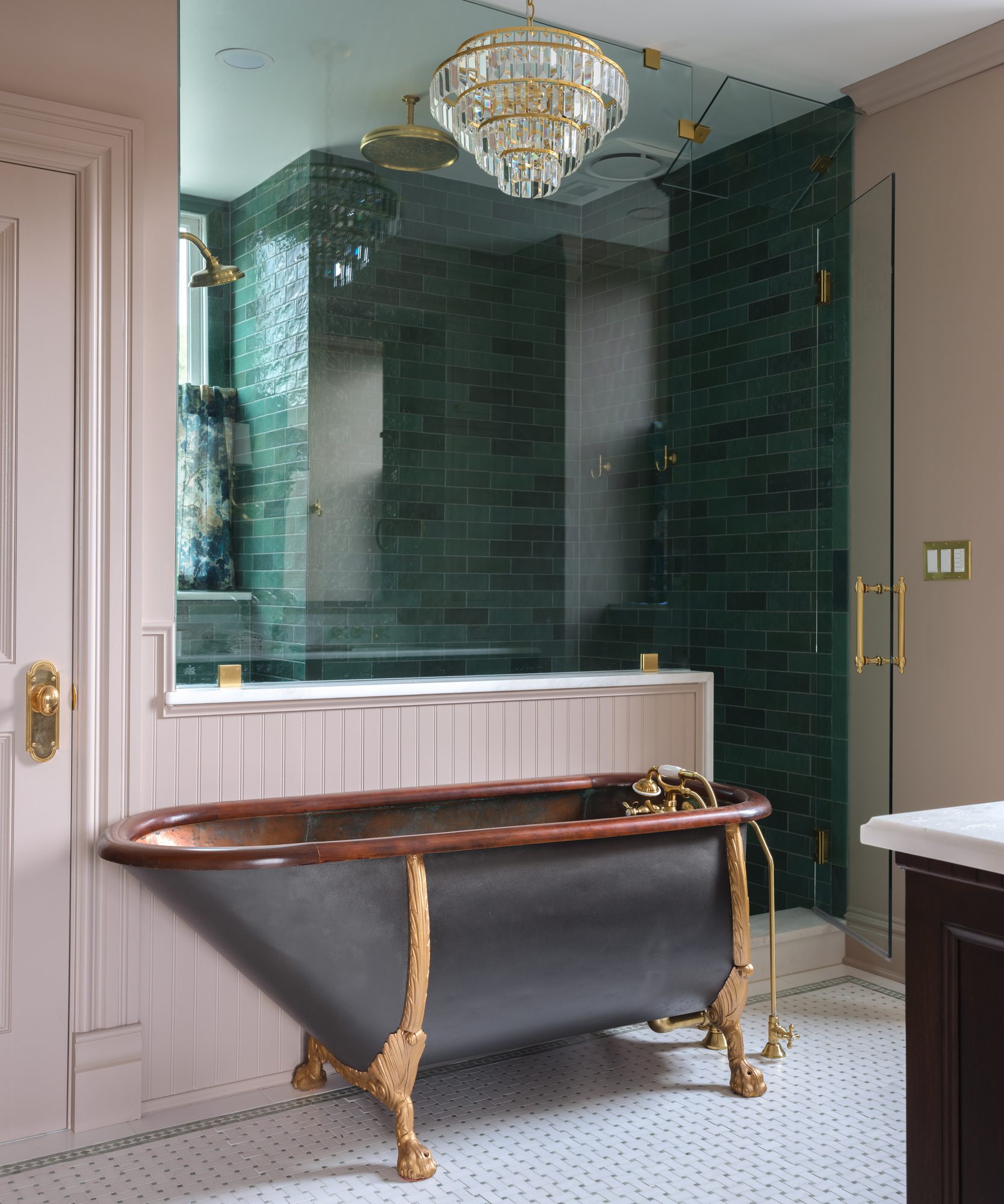 Antique copper clawfoot tub with gilded feet in front of a beadboard half wall and green-tiled shower in a historic St. Louis bathroom