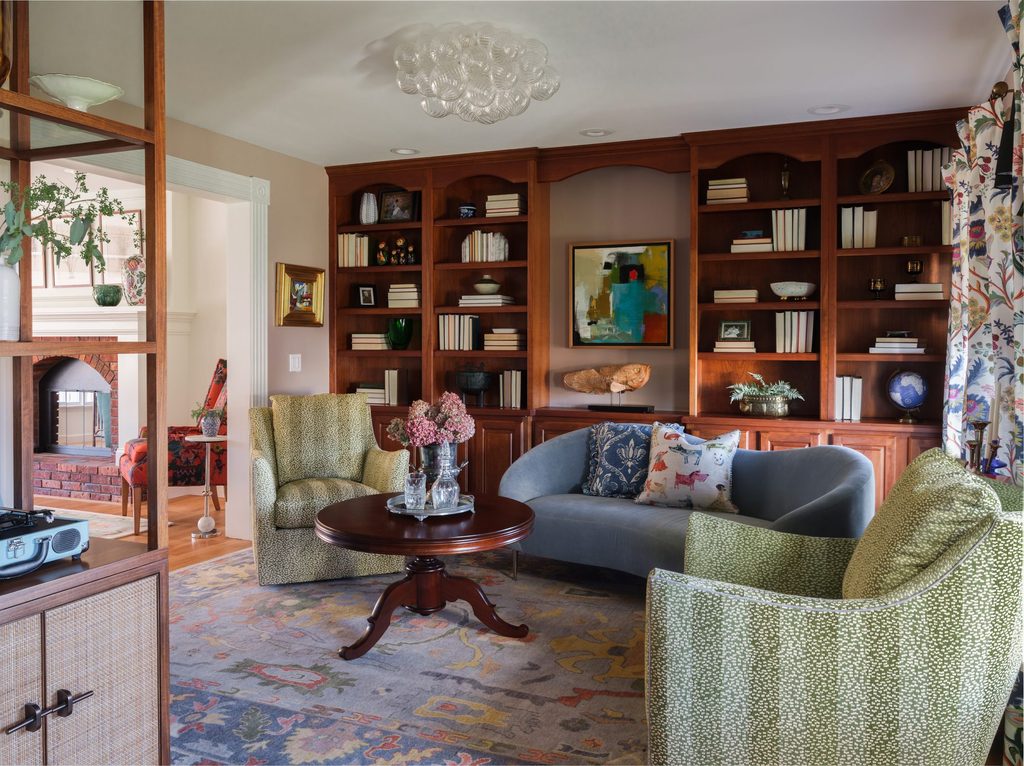Sitting room with built-in wood bookcases, a bubble glass chandelier, and a refinished heirloom pedestal coffee table