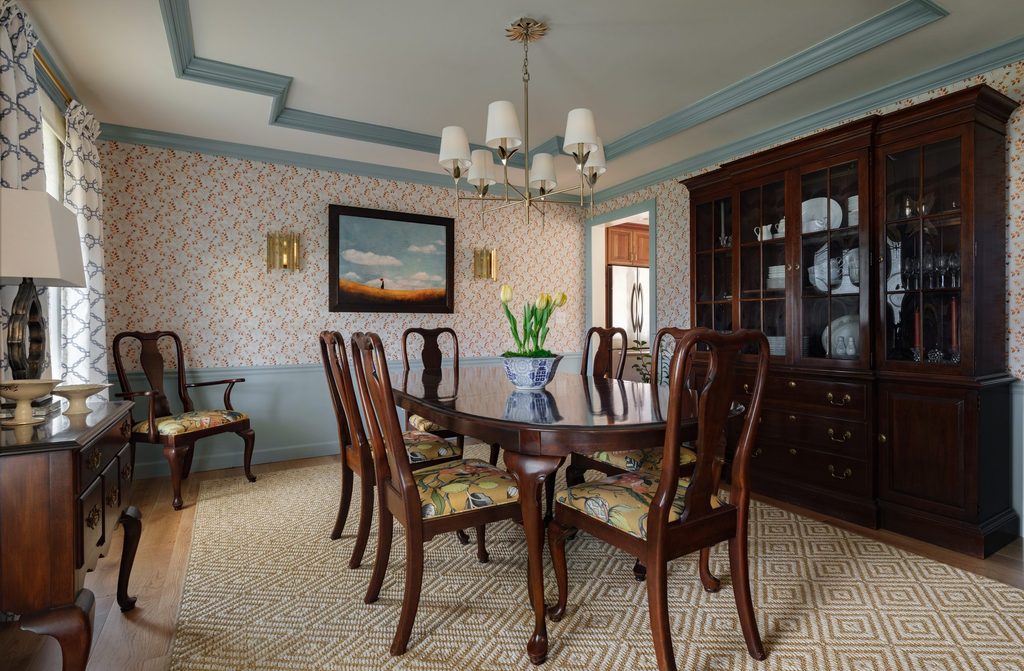 St. Charles dining room with vine wallpaper, light blue trim and ceiling molding, brass chandelier, and reupholstered chairs